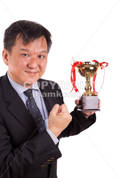 Asian business man in suit holding golden trophy - ThamKC Royalty-Free Photos