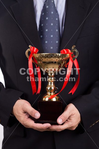 Asian business man in suit holding golden trophy - ThamKC Royalty-Free Photos