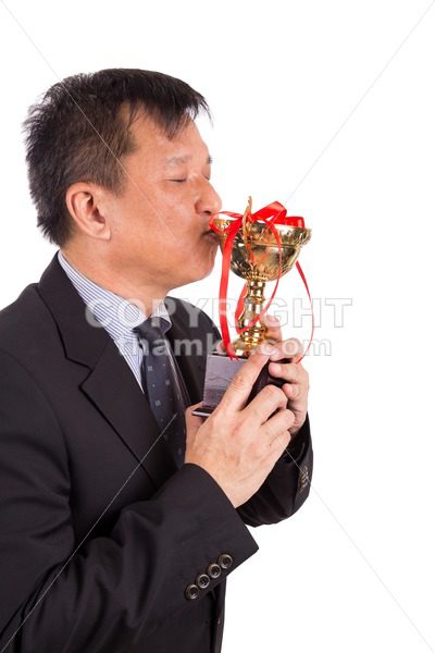 Asian business man in suit kissing golden trophy - ThamKC Royalty-Free Photos