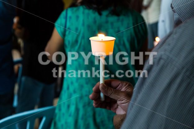 Closeup of people holding candle vigil in dark seeking hope - ThamKC Royalty-Free Photos