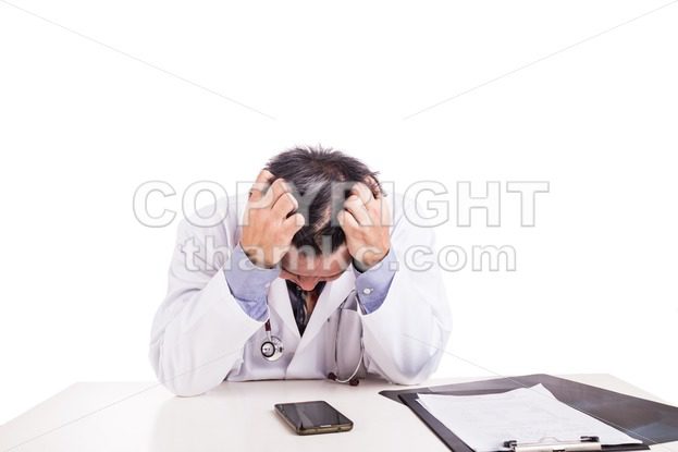 Depressed sad matured Asian doctor seated behind desk - ThamKC Royalty-Free Photos