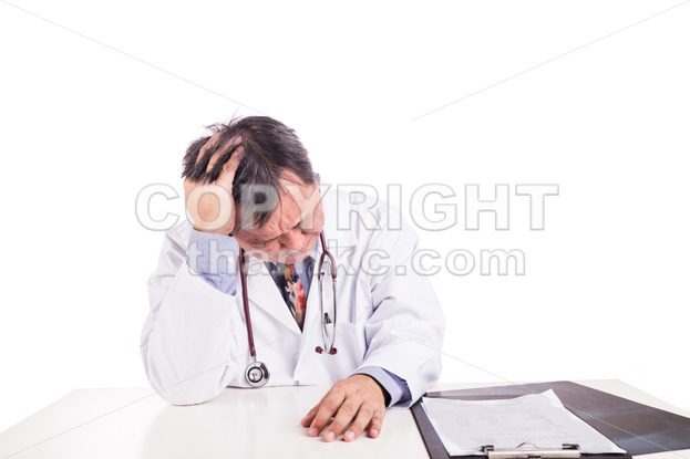 Depressed sad matured Asian doctor seated behind desk - ThamKC Royalty-Free Photos