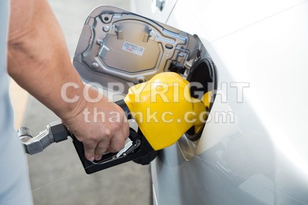 Hand with nozzle fueling unleaded gasoline into car - ThamKC Royalty-Free Photos