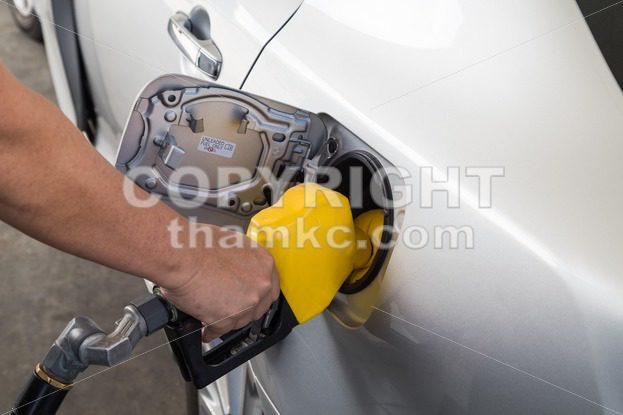 Hand with nozzle fueling unleaded gasoline into car - ThamKC Royalty-Free Photos