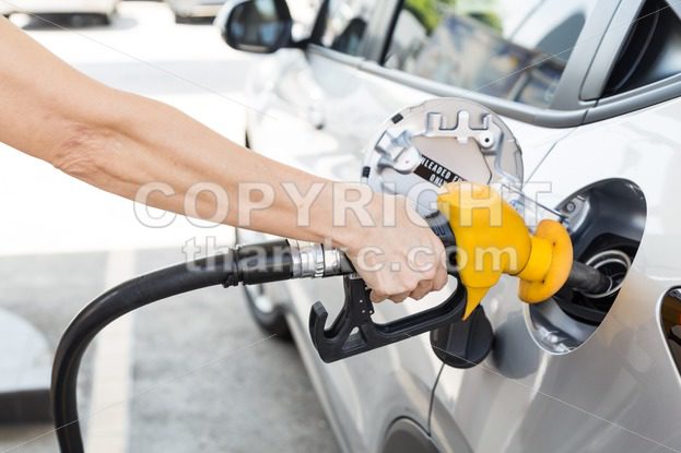 Person holding yellow nozzle filling petrol into car - ThamKC Royalty-Free Photos