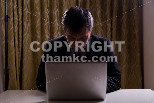 Asian businessman in suit attempting to hack computer network - ThamKC Royalty-Free Photos