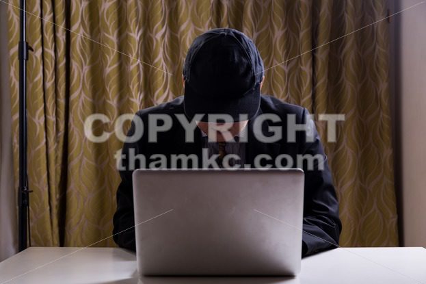Asian businessman in suit attempting to hack computer network - ThamKC Royalty-Free Photos