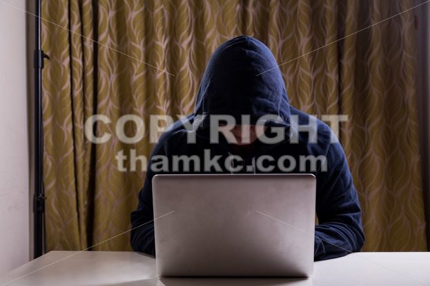 Asian hacker hacking computer network with laptop - ThamKC Royalty-Free Photos
