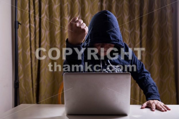 Asian hacker show fist while hacking computer network - ThamKC Royalty-Free Photos
