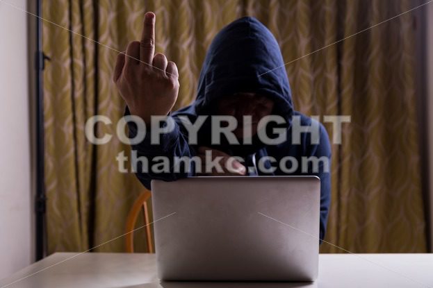 Asian hacker show middle finger while hacking computer network - ThamKC Royalty-Free Photos
