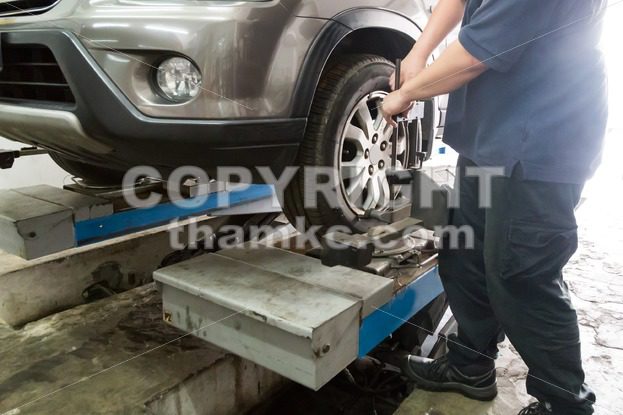 Mechanic fixing car aligner onto car wheel - ThamKC Royalty-Free Photos