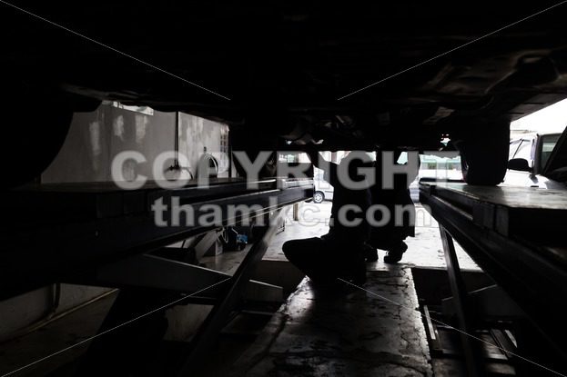 Silhouette of mechanics repairing car at small workshop garage - ThamKC Royalty-Free Photos