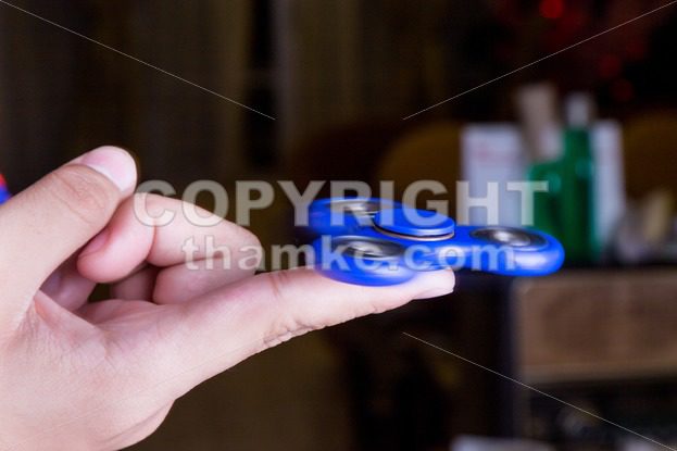 Close-up of teenager spinning a fidget spinner on finger - ThamKC Royalty-Free Photos