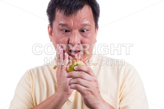 Conceptual of man holding apple with thorns fear suffer toothache - ThamKC Royalty-Free Photos