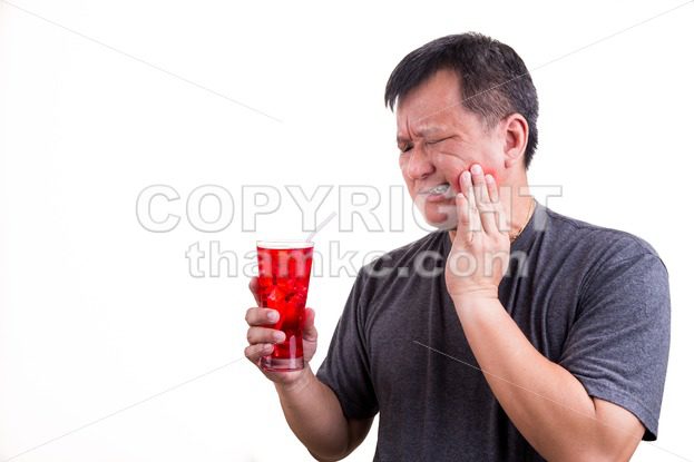 Focus on ice cold drink with man with toothache background - ThamKC Royalty-Free Photos
