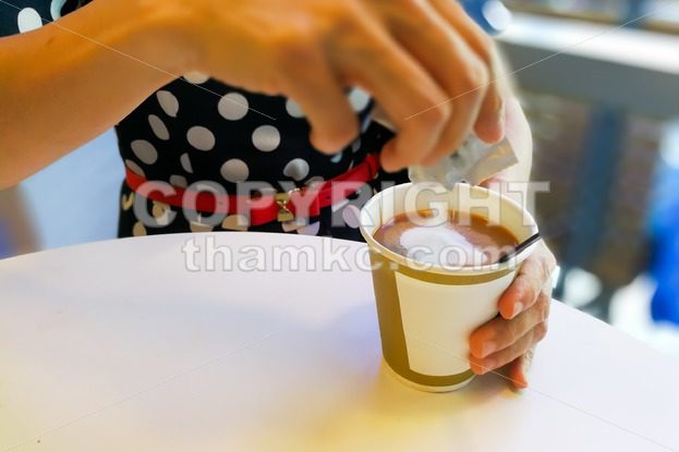 Hand pouring unhealthy non dairy creamer from sachet into coffee - ThamKC Royalty-Free Photos