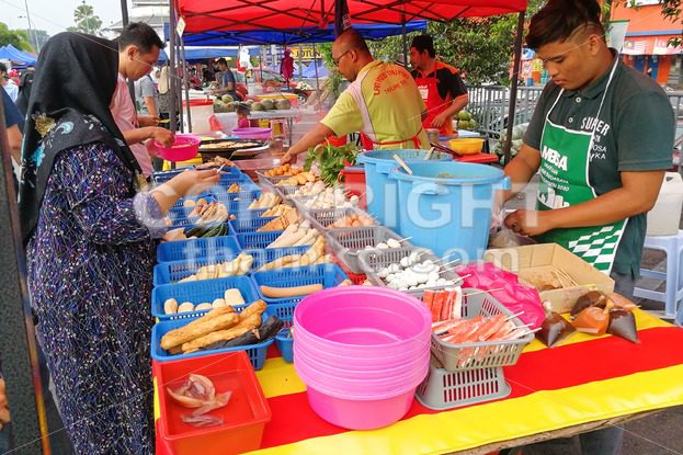 KUALA LUMPUR, MALAYSIA, May 29, 2016: Muslim shopper buying food from street vendor for breaking fast or iftar - ThamKC Royalty-Free Photos