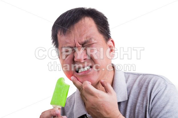 Matured man suffering intense toothache pain after biting ice cream - ThamKC Royalty-Free Photos