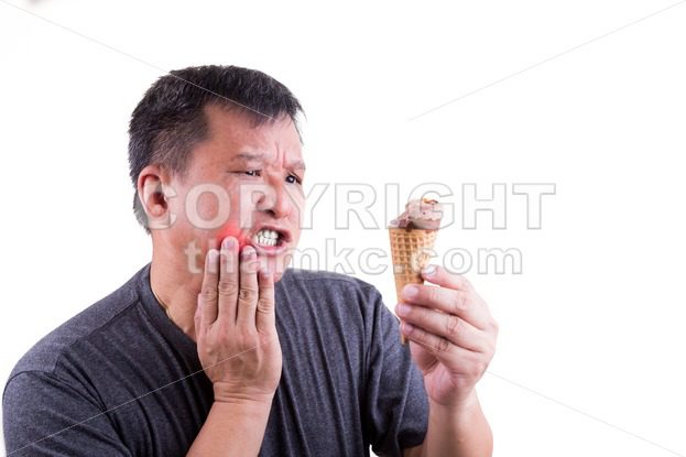 Matured man suffering intense toothache pain after biting ice cream - ThamKC Royalty-Free Photos