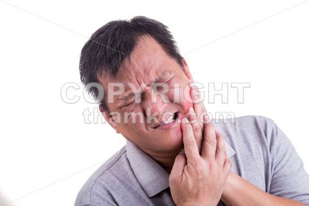 Matured man suffering intense toothache pain with hands over face - ThamKC Royalty-Free Photos