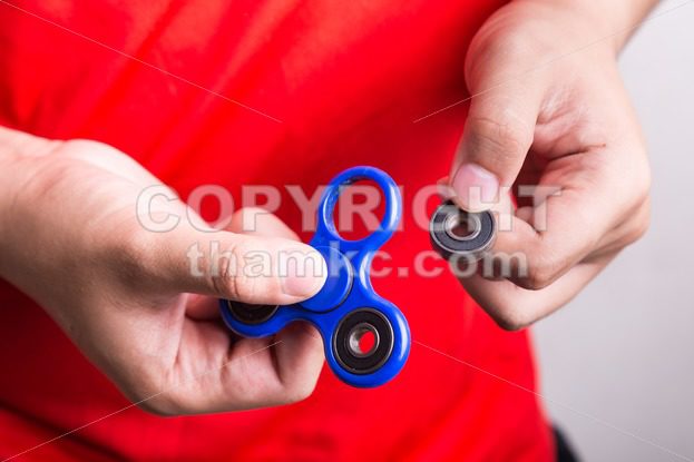 Person holding dislodged weight from fidget spinner, dangerous for kids - ThamKC Royalty-Free Photos
