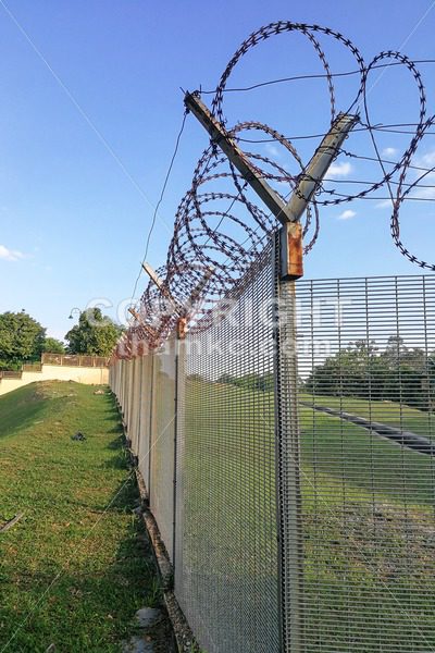 Sharp barbed wire on security fence protecti secure private space - ThamKC Royalty-Free Photos