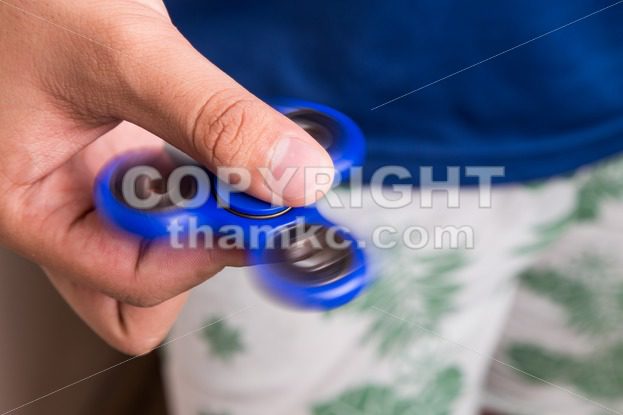 Teenager holding a spinning fidget spinner - ThamKC Royalty-Free Photos