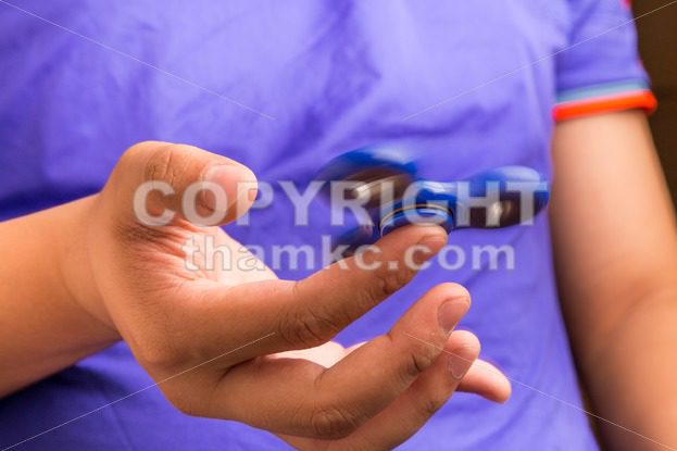 Teenager spinning a fidget spinner on finger - ThamKC Royalty-Free Photos