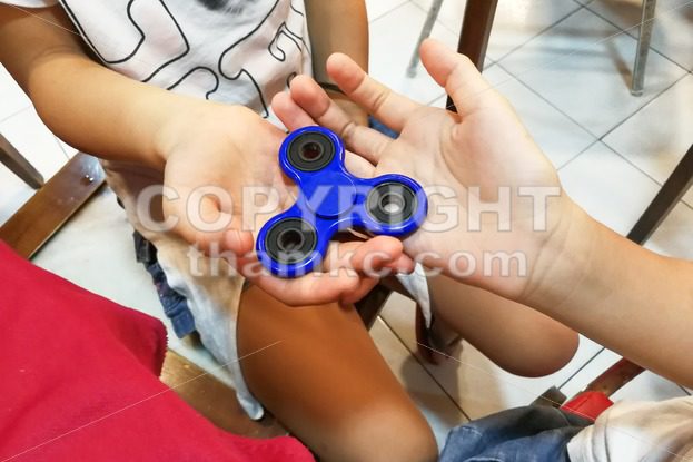 Underaged kids playing the fidget spinner. Maybe hazardous to kids. - ThamKC Royalty-Free Photos