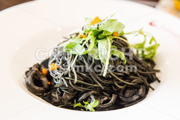 Close-up on simple squid ink pasta with squid and vegetable - ThamKC Royalty-Free Photos