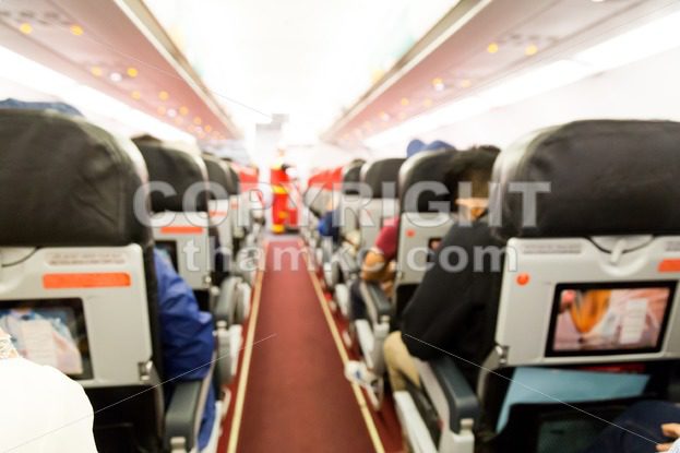 Defocused airplane cabin interior with seats and passengers - ThamKC Royalty-Free Photos
