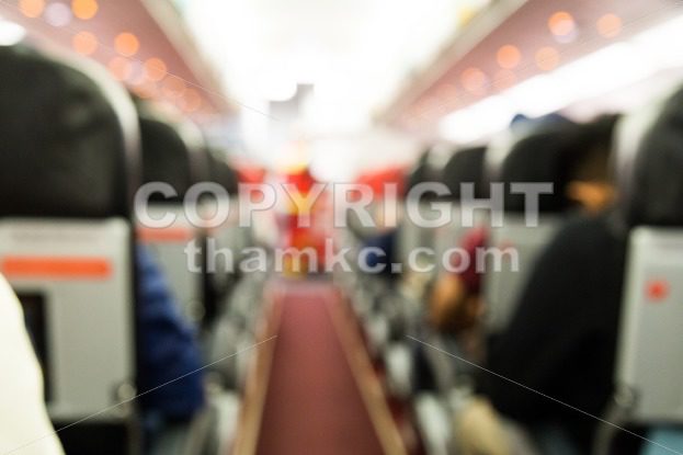 Defocused airplane cabin interior with seats and passengers - ThamKC Royalty-Free Photos