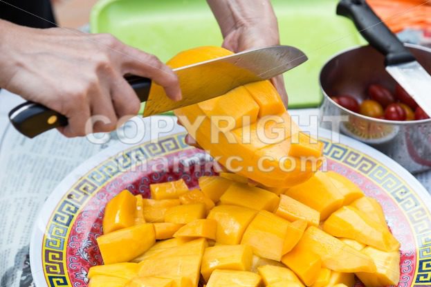 Hand holding knife cutting sweet delicious organic mango - ThamKC Royalty-Free Photos