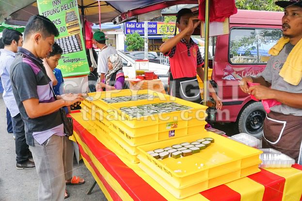 KUALA LUMPUR, MALAYSIA, June 2, 2017: Muslim shopper buying sweet desserts from street stall vendor for breaking fast or iftar - ThamKC Royalty-Free Photos