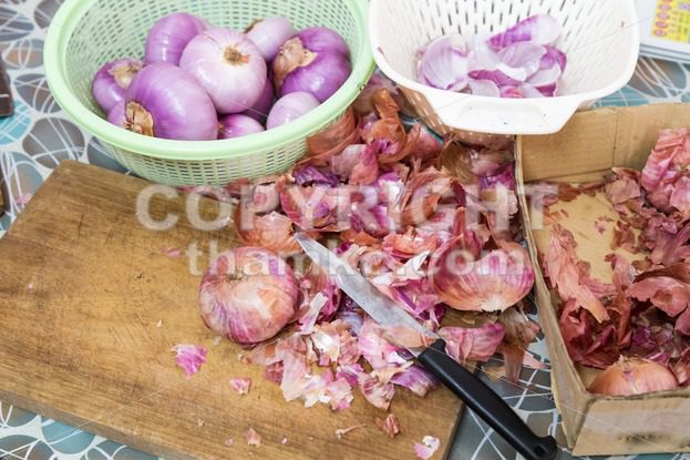 Onion skin being prepared peeled with knife, chopping board colander - ThamKC Royalty-Free Photos