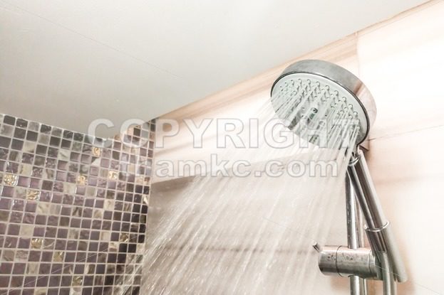 Shower head with refreshing water droplets spray in bathroom - ThamKC Royalty-Free Photos