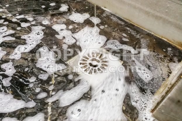 Soap foam and water flowing into bathroom drainage hole - ThamKC Royalty-Free Photos
