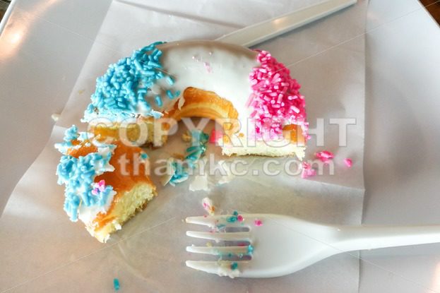 Unfinished donut glazed with sugar coating and sprinkles on plate - ThamKC Royalty-Free Photos