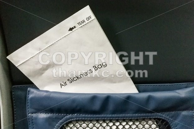 Air sickness bag tucked behind airplane seat pocket - ThamKC Royalty-Free Photos