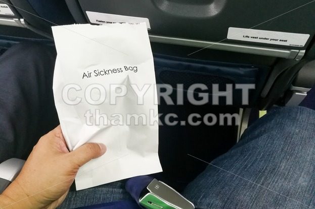 Airsick nauseous person holding the air sickness vomit bag - ThamKC Royalty-Free Photos