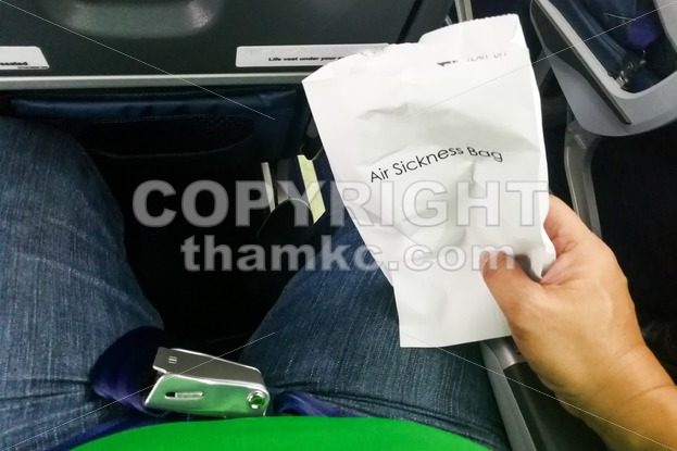 Airsick nauseous person holding the air sickness vomit bag - ThamKC Royalty-Free Photos