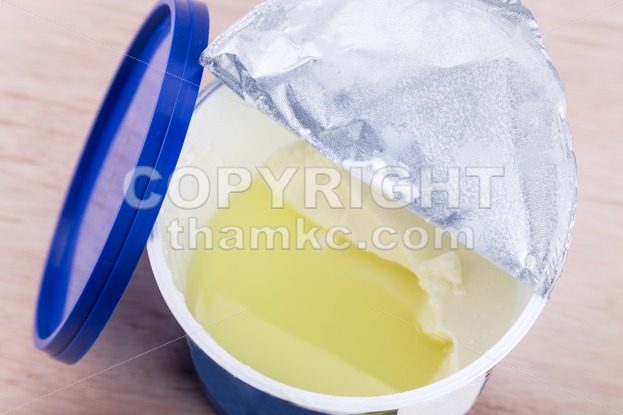 Layer of whey protein formed on top of packaged yogurt - ThamKC Royalty-Free Photos